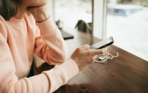 Personne pensive avec écouteurs regardant son smartphone